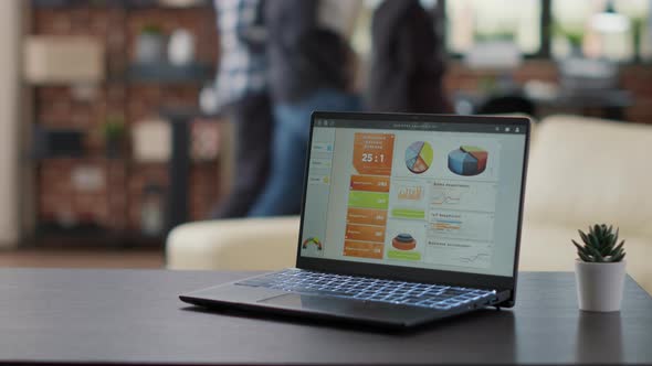 Laptop Screen with Financial Charts and Graphs on Office Desk alt