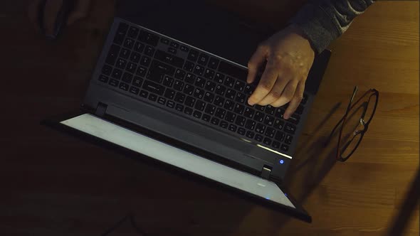 Man types on a laptop in the room at the night