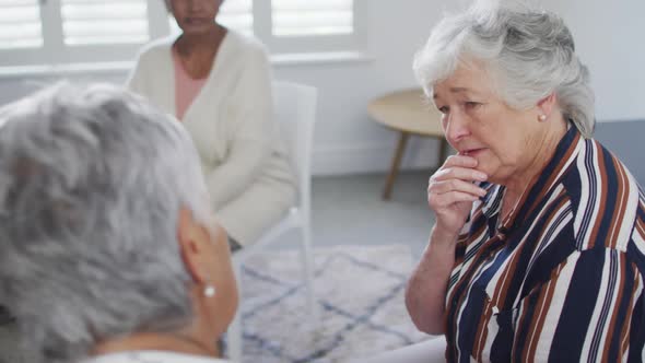 Diverse group of senior friends giving support to caucasian female friend on meeting alt