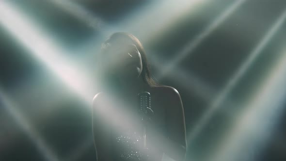 Female Musician with a Professional Retro Microphone Performs on Stage in the Dark. A Sexy Woman in alt
