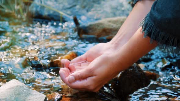 Taking water with handfuls of mountain stream in slow motion. alt