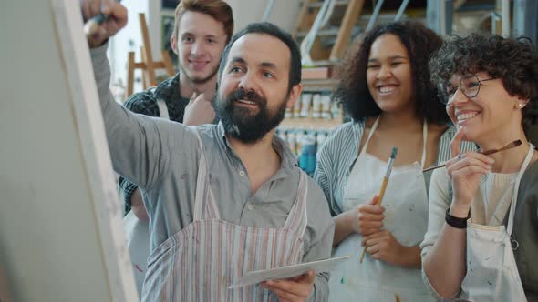 Slow Motion of Skilled Middle-aged Artist Painting Picture and Talking To Group of Students alt