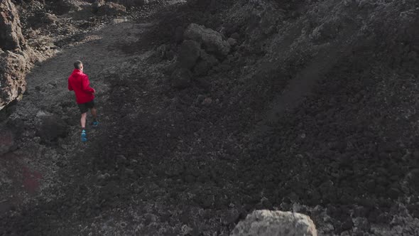 Anonymous Sportive Male Traveler Running Across Black Lava Rocks