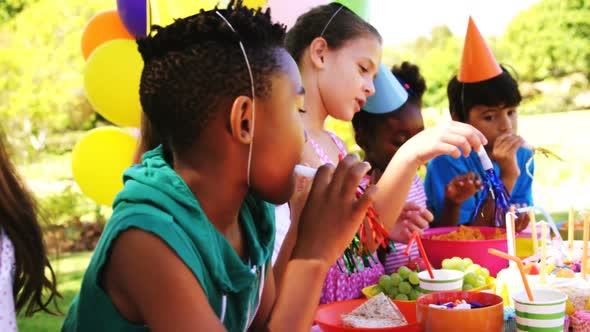 Kids standing near table laid with food and celebrating a birthday alt