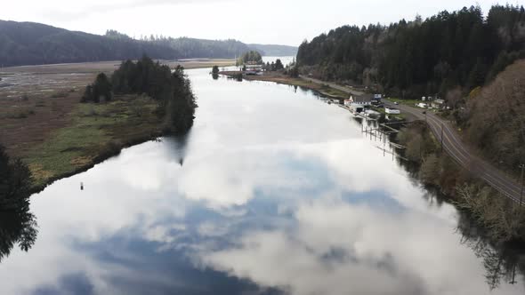 drone flight over tranquil Siuslaw River in Florence, Oregon, USA at daytime. sky reflected on water alt