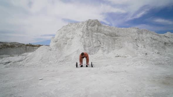 Strong shirtless athlete taking heavy barbell outdoors. alt