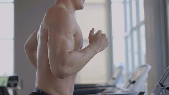 Muscular man running in treadmill in the fitness