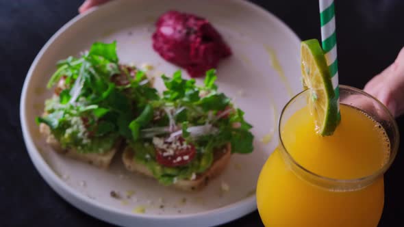 Table Setting with Fresh Avocado Toasts with Salad on a Platter and Orange Fresh Juice in a alt