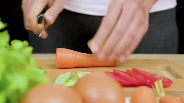 Woman's hands using kitchen knife cutting fresh carrots for making healthy sandwich