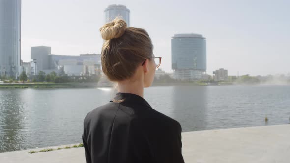 Business Woman Walking Down Sidewalk Near River alt
