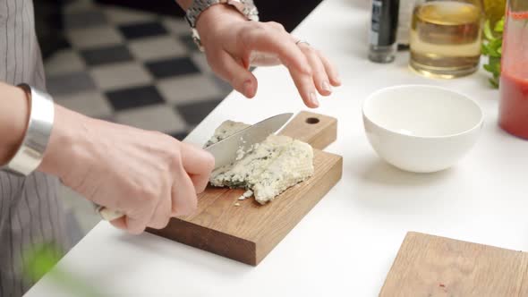 Crop chef cutting blue cheese on board alt