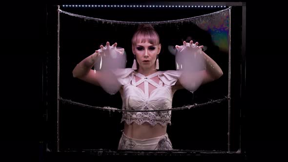 Young Girl Does Tricks with Soap Bubbles. She Takes Two Big Bubbles with Her Hands alt