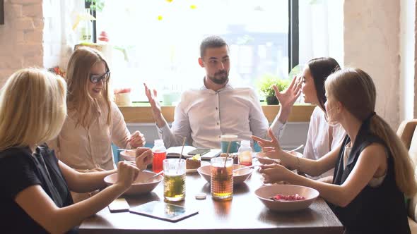 Five Multiethnic Friends Sitting at Table in Cafe, Talking, Cheering, Telling Each Other Stories alt