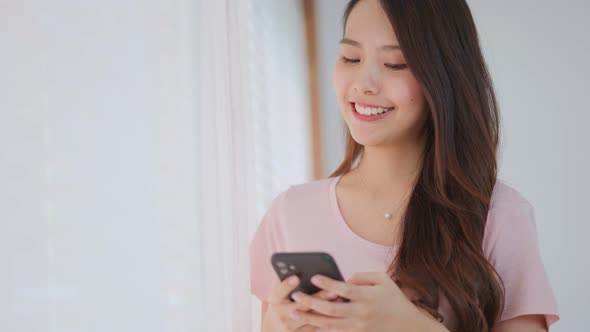 Asian beautiful girl spend leisure time, texting chat message on smartphone in living room at home. alt