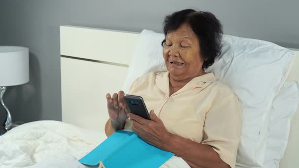 happy senior woman using mobile phone in a bed alt