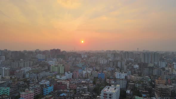 Aerial Over Khilgaon Thana Cityscape With Hazy Orange Sunset Skies. Pedestal Up alt