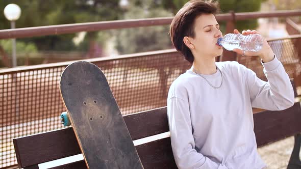 Tired Teenage Girl Sitting on Chair and Drinking Water From the Bottle