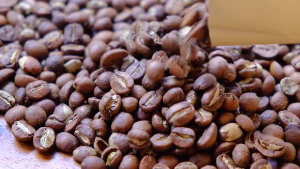 Light roasted coffee beans falling on the wooden background