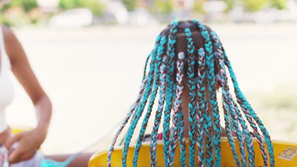 A Girl in a Suit Weaves African Braids in Her Hair on a Sunny Day alt