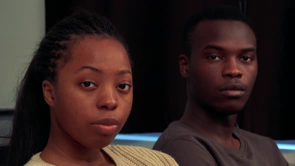 Young Black Couple Look To Camera with Serious Face in Living Room - Closeup alt