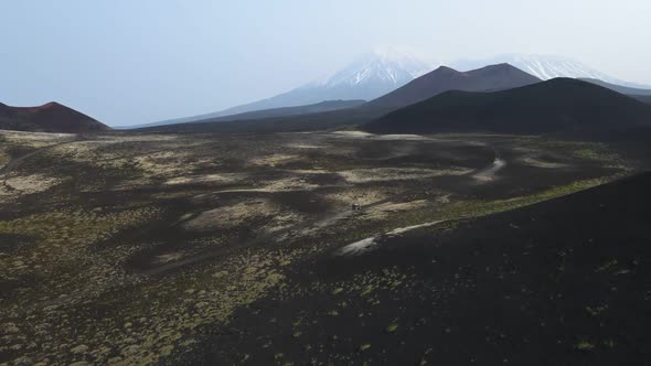 cars drive on black earth overlooking volcanoes