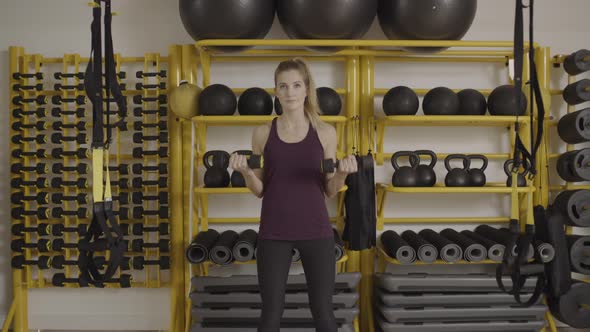 Young woman lifting weights in gym