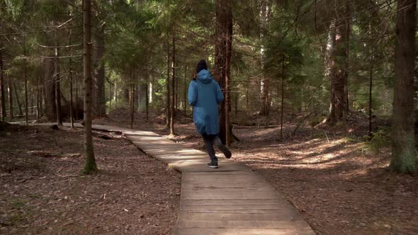 Woman in a Blue Raincoat Makes A Run On The Forest Road