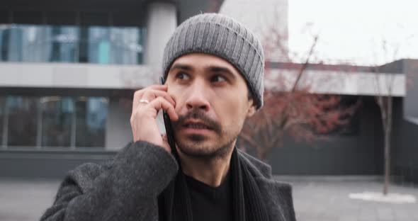 Confident Young Businessman Talks By Phone with Partner While Walking