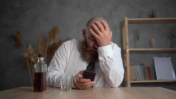 Bankruptcy and Portrait of a Bearded Businessman in Formalwear Drinking a Glass of Whiskey Sitting alt