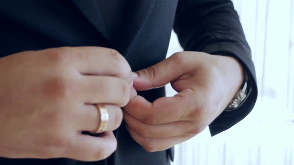 A Man is Fastening a Button on His Jacket Closeup
