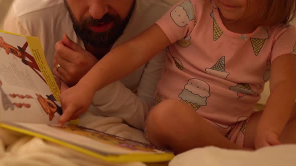 Daughter and Father are Reading Book in Tent