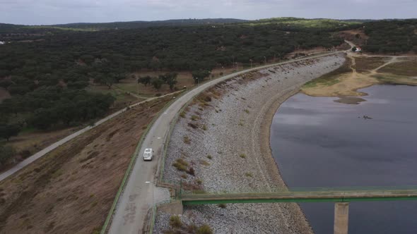 Camper van motorhome drone aerial view passing a dam road with the lake reservoir in Divor Dam in Al alt