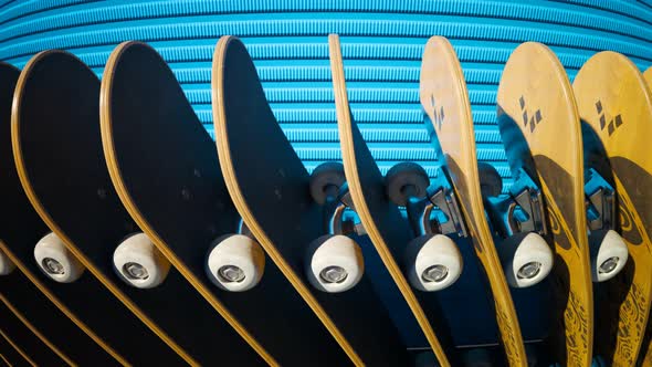 An endless row of standing skateboards with a blue wall in the background. 4KHD alt