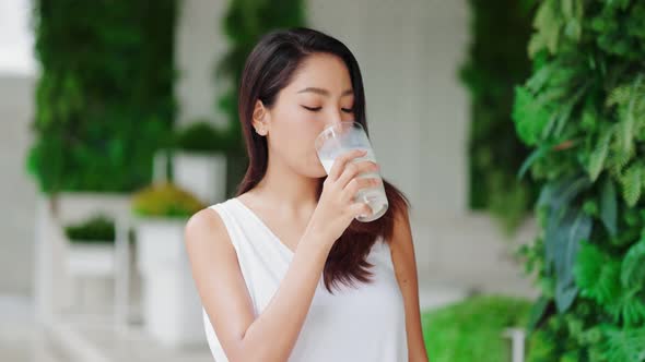 Attractive Asian woman drinking milk and smiling at home close up face.healthy life alt