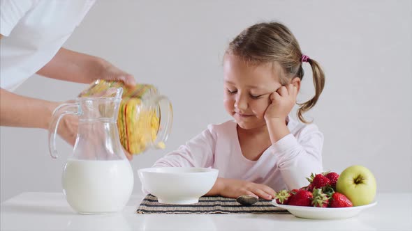 Little Girl is Waiting Her Breakfast Cornflakes with Milk alt