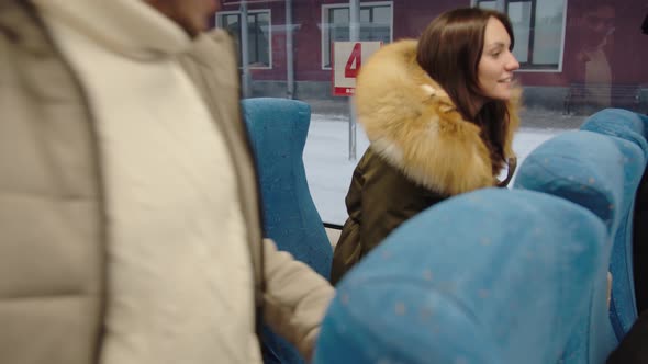 A Middleaged Couple Takes Their Seats in a Train Carriage in Winter Clothes