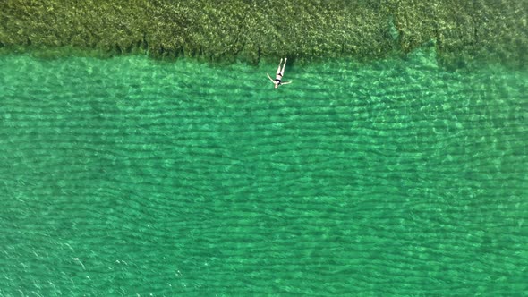 A woman swims in the sea aerial view 4K alt
