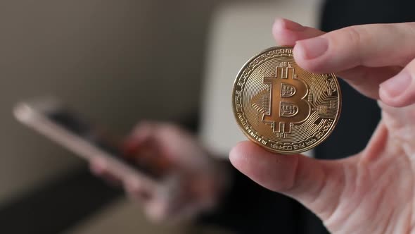 Woman Using a Smartphone with a Hand and Holding a Bitcoin Coin with the Other