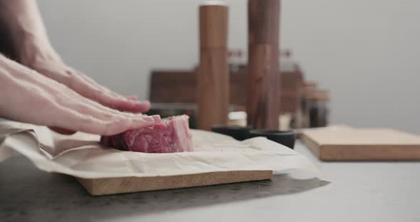 Slow Motion Man Massaging New York Steak with Spices on Countertop alt
