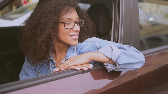 Happy Young Smiling African American Woman Black Haired Driver in Glasses Sitting in New Brown Car
