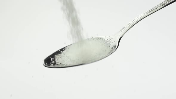 Very Beautiful Stunning Bright White Sugar Sugar Crumbles Into a Shiny Teaspoon alt