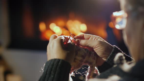 Hands of an Old Woman Knitting Near a Fireplace in the Evening alt