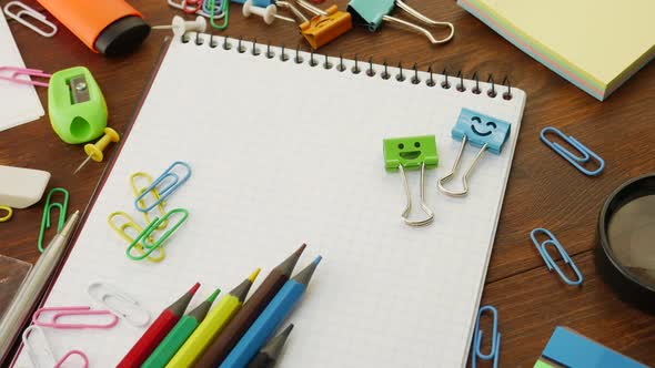 Smiles Blue and Green Binder Clips on Notebook with Multi-Colored Pencils and Paper Clips