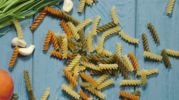 Raw Fusilli Pasta Falling Down On The Blue Wooden Table