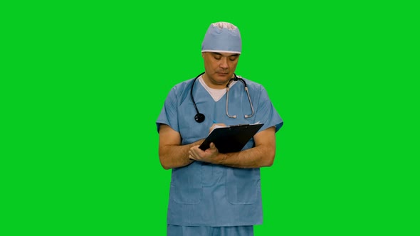 Mid Adult Doctor In Uniform Writing On Clipboard