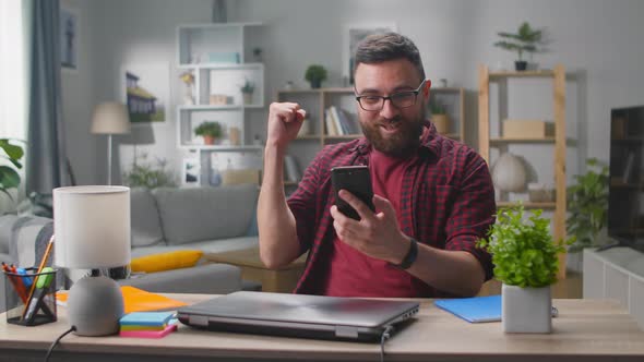 Man Winner Hold Smartphone Feel Amazed Overjoyed with Mobile Online Bet Bid App Game Win alt