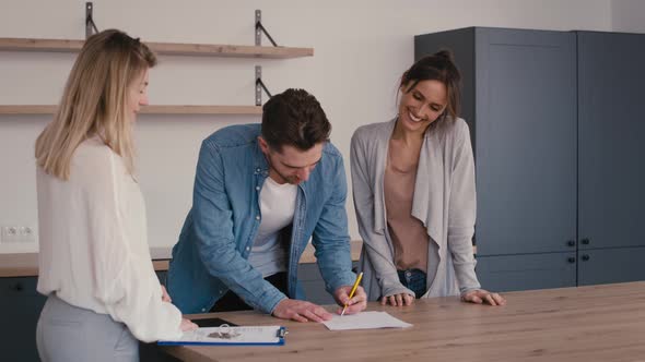 Young caucasian couple signing house purchase agreement with a real estate agent. alt