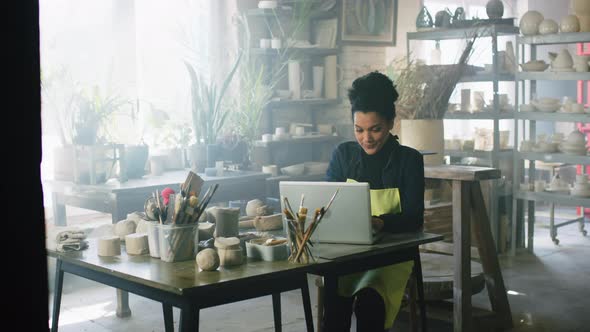 Woman Is Working On Laptop In Pottery Studio