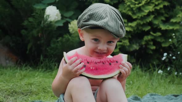 Happy Toddler Boy Eating Watermelon Sitting on Grass alt