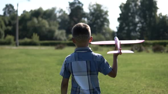 The Boy Launches a Toy Plane in the Park in Sunny Weather Having a Good Mood alt